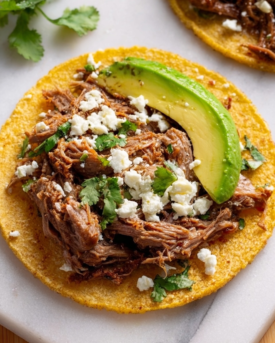 Three yellow corn tortillas lie flat on a white marbled surface covered with a sheet of white parchment paper. Each tortilla has a layer of shredded meat topped with small crumbles of white cheese and sprinkled with green cilantro leaves. On top of the meat and cheese, there are two or three slices of fresh bright green avocado arranged neatly. Around the tortillas, there are scattered pieces of cilantro. To the left, there is a white bowl filled with four lime wedges, and nearby is a small clear bowl with white cheese. On the right side, a white bowl contains a chunky red salsa, with two lime wedges placed beside it. A woman's hand holding a wooden utensil appears at the top. The overall look is fresh and colorful with warm golden, green, and white tones. photo taken with an iphone --ar 4:5 --v 7