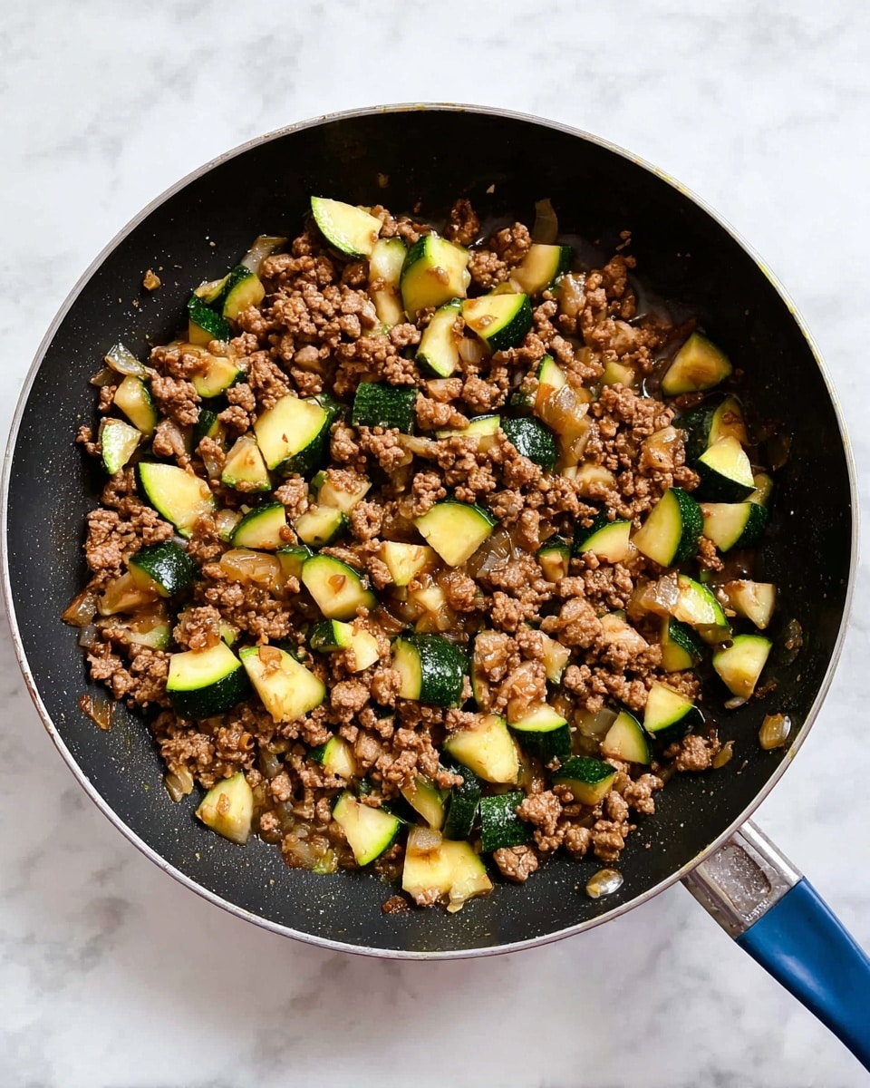 A white bowl filled with two main layers, on the left side there is a thick layer of light beige cooked rice with a soft texture, and on the right side there is a thick layer of ground meat mixed with chunks of green zucchini with bright green skin and light yellow inside, garnished with small pieces of green onion on top. The bowl is placed on a white marbled surface with some green onions and a small bowl of red chili flakes around it, alongside a fork and a white cloth napkin with gray stripes. photo taken with an iphone --ar 4:5 --v 7