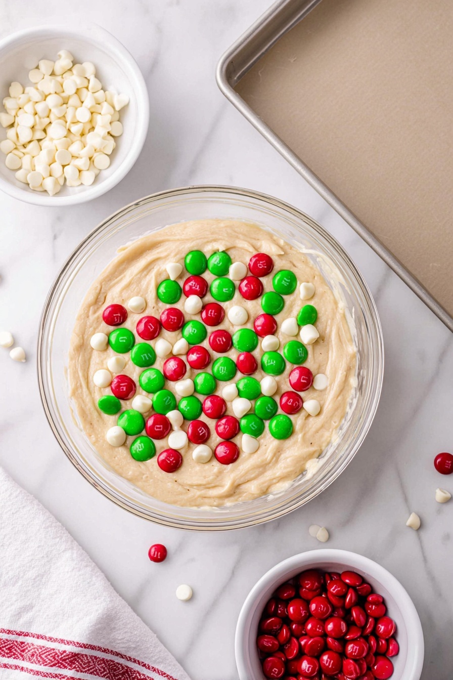 Festive White Cake Mix Cookies, holiday cookie recipes, easy Christmas cookies, colorful M&Ms cookies, quick holiday treats - A white plate with raised dot patterns holds a stack of round cookies, about two layers high, with a soft, slightly cracked pale beige surface. Scattered across the cookies are bright red and green candy pieces, along with white chocolate chips and red, green, and white sprinkles giving the cookies a festive look. Some candy pieces are embedded within the cookie dough, causing slight smudges of color blending into the cookie surface. The plate sits on a white marbled textured surface, with part of a white towel with a red stripe visible in the corner. photo taken with an iphone --ar 2:3 --v 7
